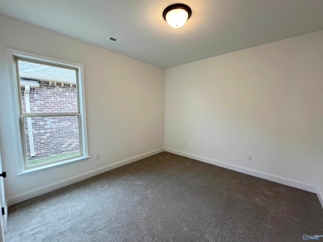 spare room with dark colored carpet and a wealth of natural light