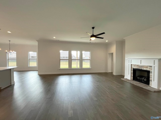 unfurnished living room featuring a stone fireplace, ceiling fan with notable chandelier, and dark hardwood / wood-style flooring