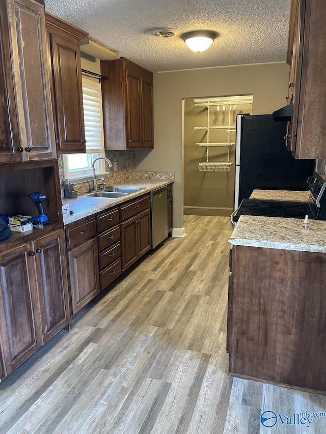 kitchen featuring stainless steel appliances, dark brown cabinets, sink, and light hardwood / wood-style floors