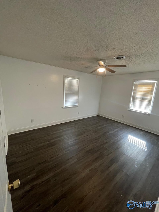 empty room featuring ceiling fan, dark wood-type flooring, and a textured ceiling