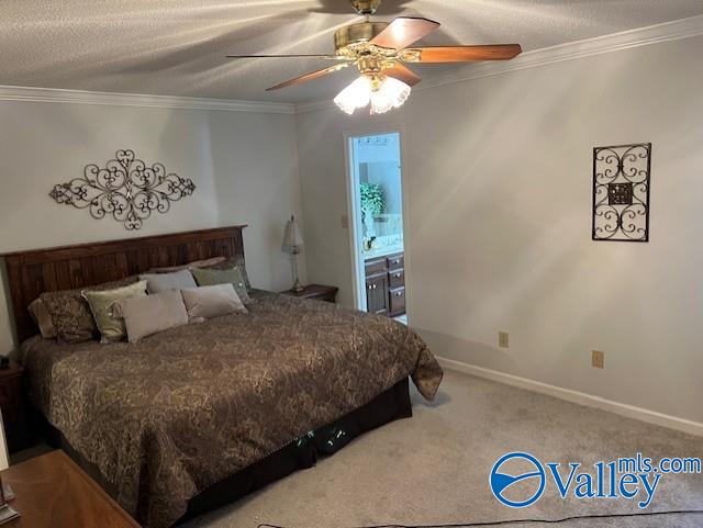 carpeted bedroom with a textured ceiling, ensuite bath, ceiling fan, and crown molding