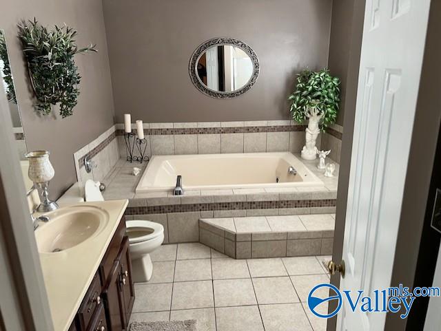 bathroom with tile patterned floors, tiled bath, vanity, and toilet