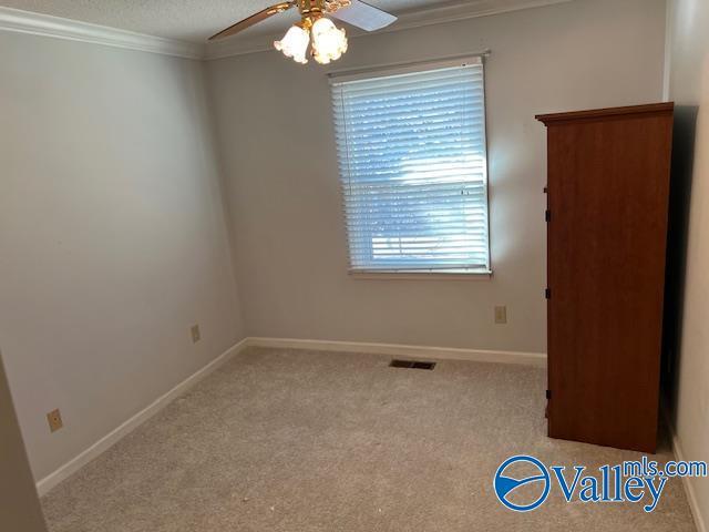 unfurnished room with crown molding, ceiling fan, light colored carpet, and a textured ceiling