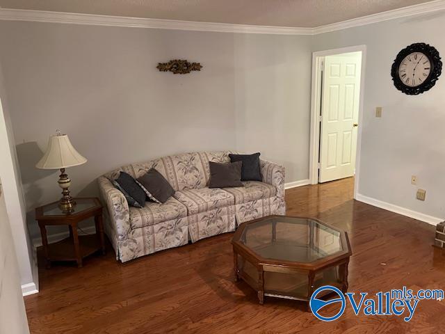 living room with dark wood-type flooring and ornamental molding