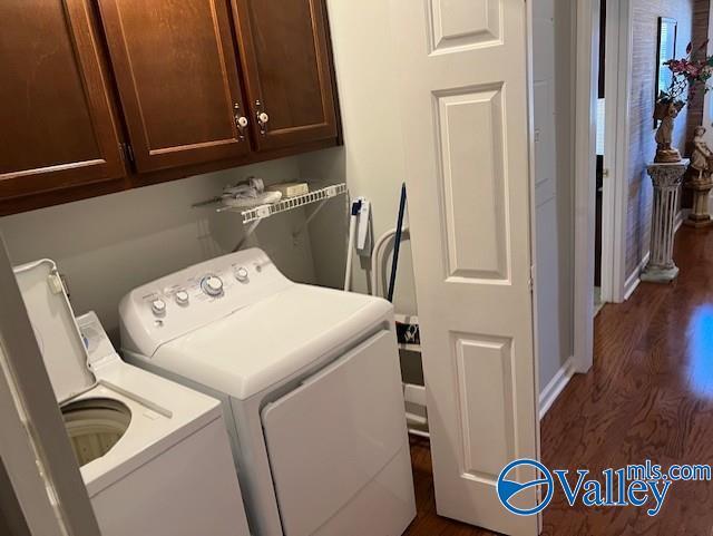 laundry area featuring cabinets, dark hardwood / wood-style floors, and washing machine and clothes dryer