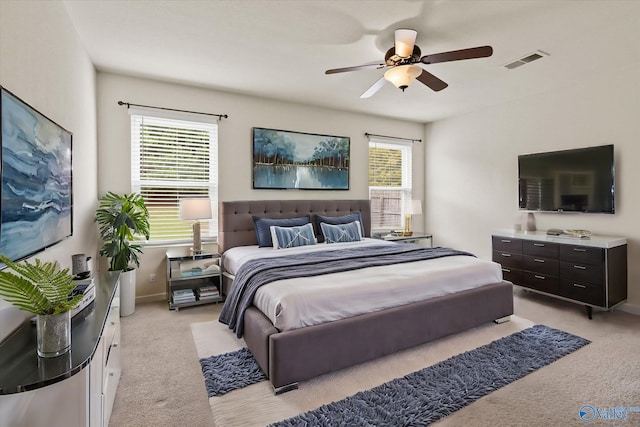 bedroom with light colored carpet, multiple windows, and ceiling fan