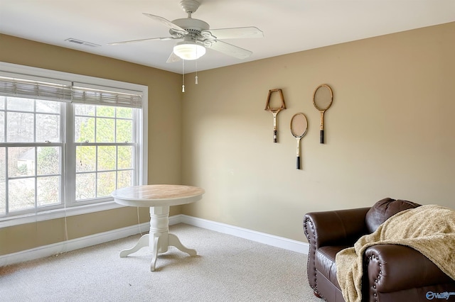 living area featuring light carpet and ceiling fan