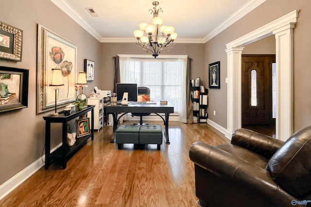 office space with light wood-type flooring, ornate columns, crown molding, and an inviting chandelier
