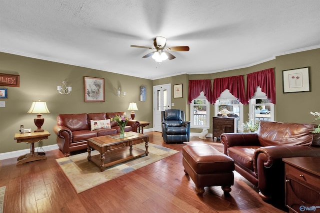 living area with baseboards, a ceiling fan, ornamental molding, hardwood / wood-style floors, and a textured ceiling