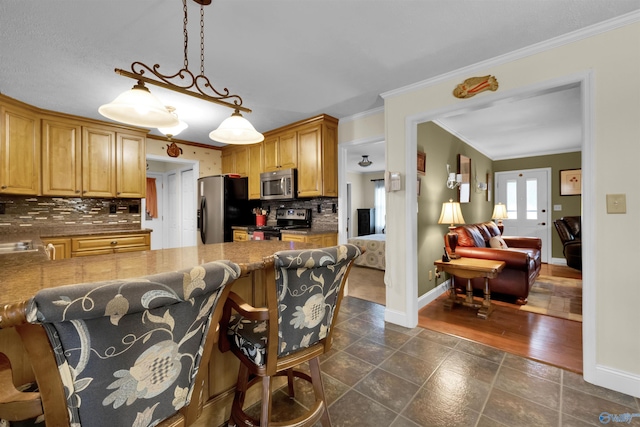 kitchen with baseboards, appliances with stainless steel finishes, hanging light fixtures, crown molding, and backsplash