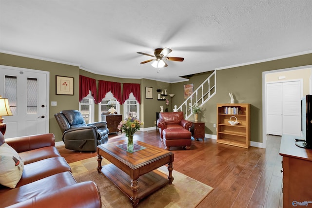 living room with baseboards, a textured ceiling, ornamental molding, and wood finished floors