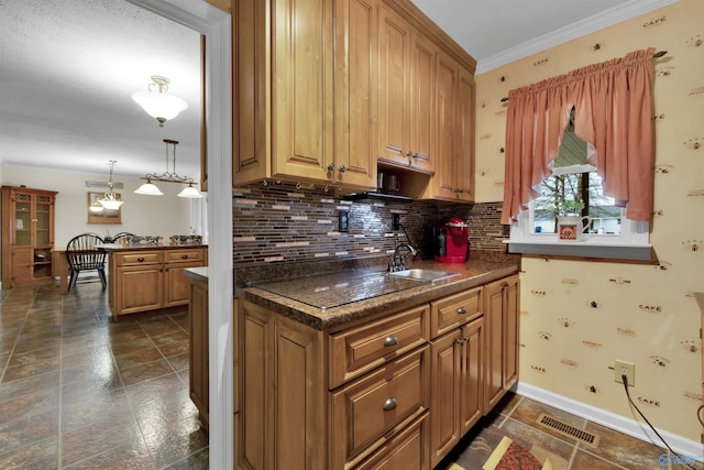 kitchen featuring brown cabinets, dark countertops, visible vents, and a sink