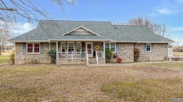 view of front of house featuring covered porch, brick siding, roof with shingles, and a front yard