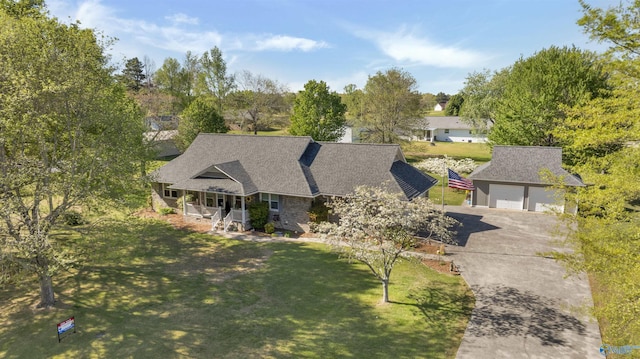 view of front facade with covered porch, a front yard, roof with shingles, and concrete driveway