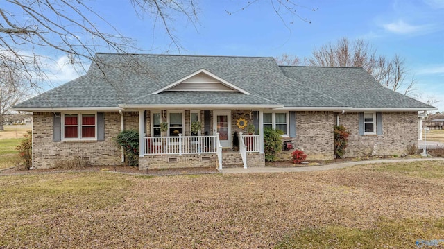 view of front facade featuring brick siding, a front lawn, a porch, and roof with shingles