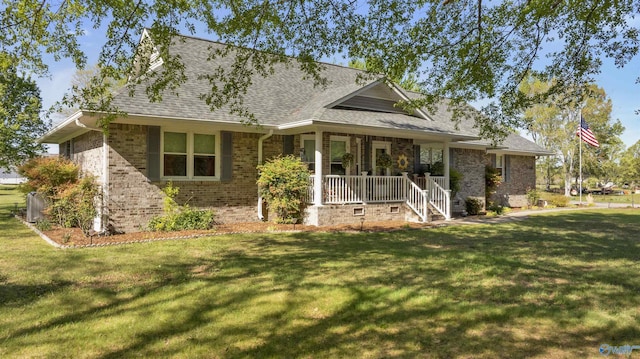 rear view of property with a lawn, brick siding, roof with shingles, and covered porch
