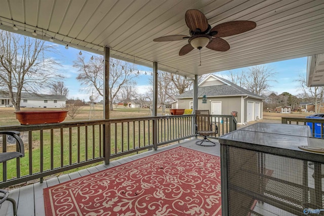 wooden deck with an outbuilding, a yard, ceiling fan, and a garage