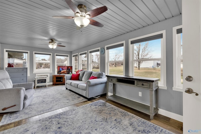 sunroom with baseboards, heating unit, and wood finished floors
