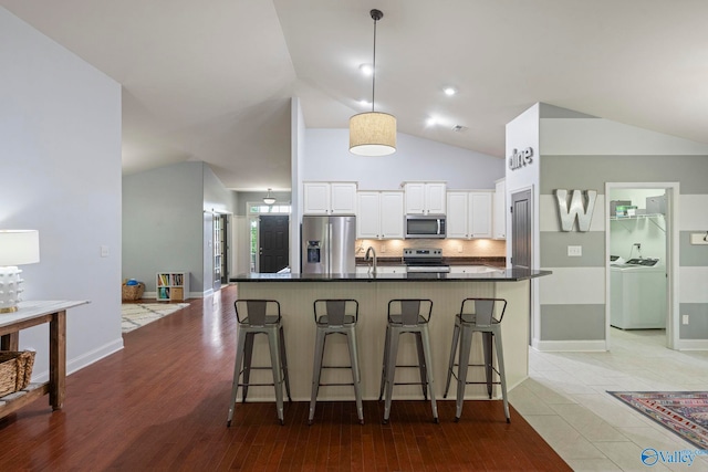 6807 Breyerton Way SE, Owens Cross Roads, AL 35763 - kitchen featuring appliances with stainless steel finishes, washer and clothes dryer, lofted ceiling, white cabinets, and a breakfast bar