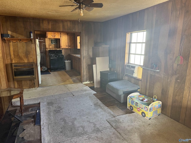 misc room with ceiling fan, wooden walls, heating unit, and a textured ceiling