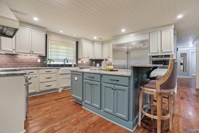 kitchen with a kitchen island, light hardwood / wood-style flooring, white cabinetry, appliances with stainless steel finishes, and a breakfast bar area