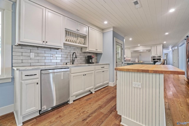 kitchen with appliances with stainless steel finishes, white cabinetry, a kitchen island, and light hardwood / wood-style flooring