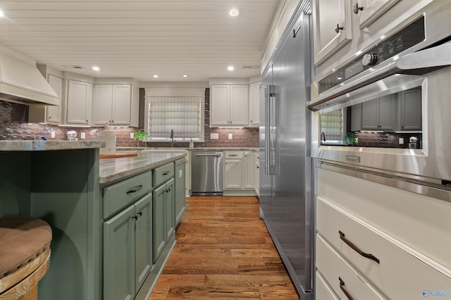 kitchen featuring white cabinets, tasteful backsplash, green cabinetry, appliances with stainless steel finishes, and dark hardwood / wood-style floors