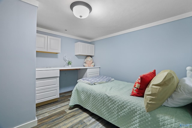 bedroom featuring ornamental molding, built in desk, and dark hardwood / wood-style flooring