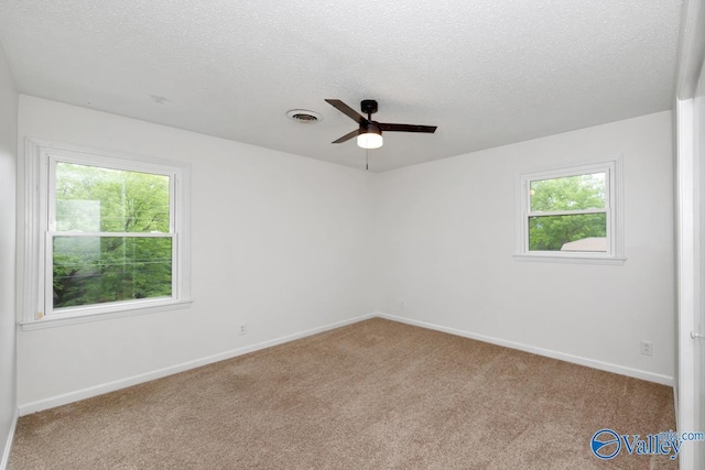 empty room with a textured ceiling, carpet floors, visible vents, and a ceiling fan