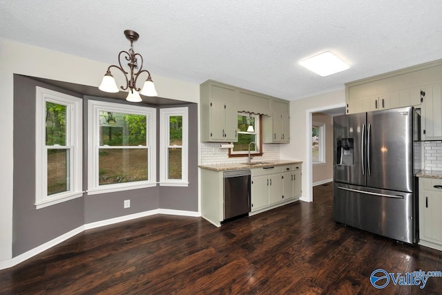 kitchen with stainless steel appliances, a sink, baseboards, a notable chandelier, and decorative backsplash