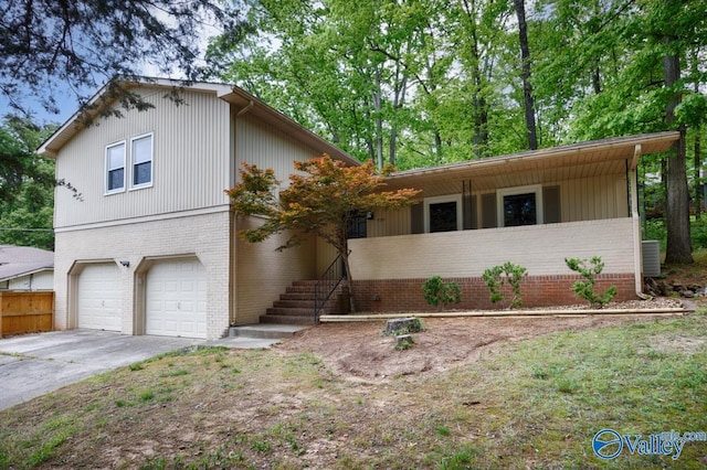 split level home with brick siding, driveway, a garage, and fence