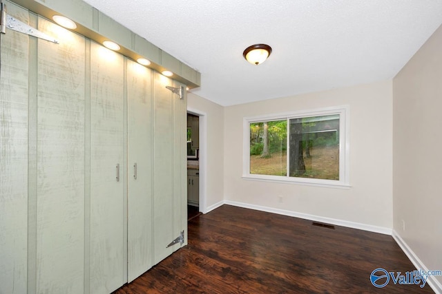 unfurnished bedroom with baseboards, wood finished floors, and visible vents