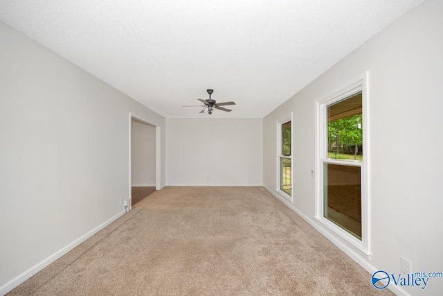 unfurnished room with light colored carpet, baseboards, and a ceiling fan