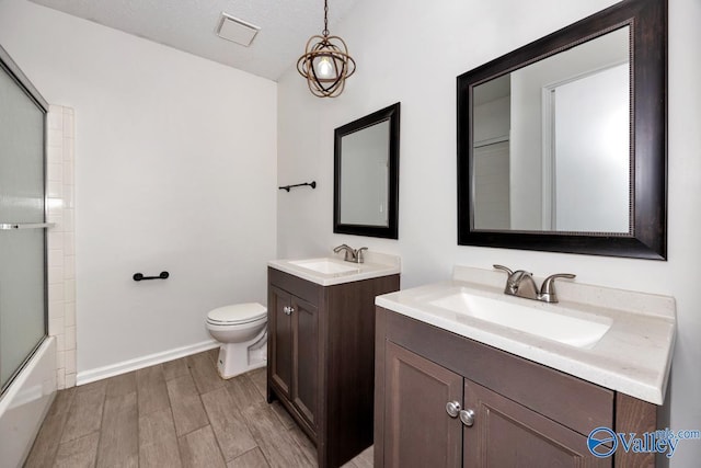 bathroom featuring toilet, wood finished floors, a sink, baseboards, and visible vents