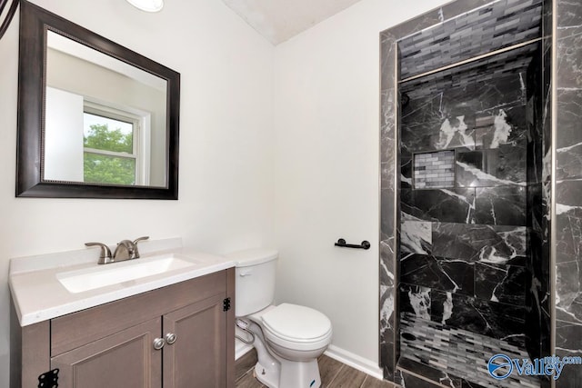 bathroom featuring toilet, vanity, wood finished floors, and a stall shower