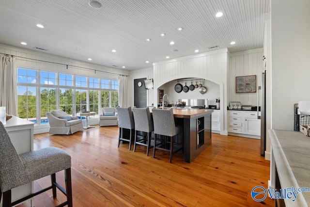 kitchen with a breakfast bar, arched walkways, light wood-type flooring, and recessed lighting