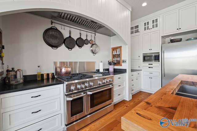 kitchen with butcher block countertops, white cabinetry, high end appliances, and light wood-type flooring