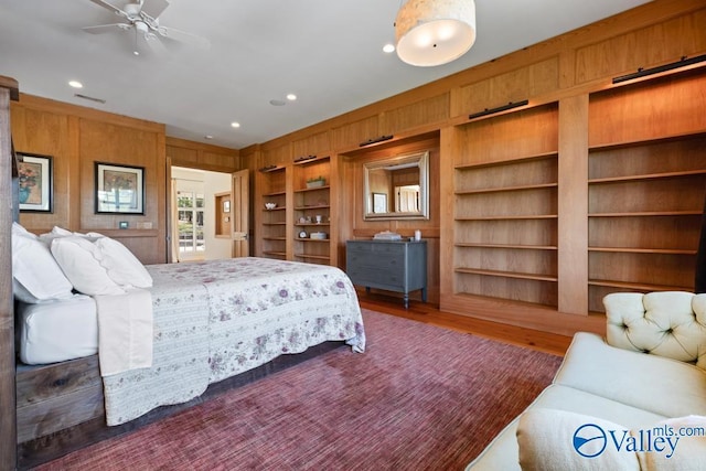 bedroom with wooden walls, visible vents, recessed lighting, and wood finished floors