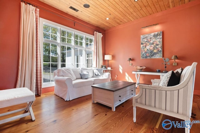 living room featuring visible vents, light wood-type flooring, and wooden ceiling