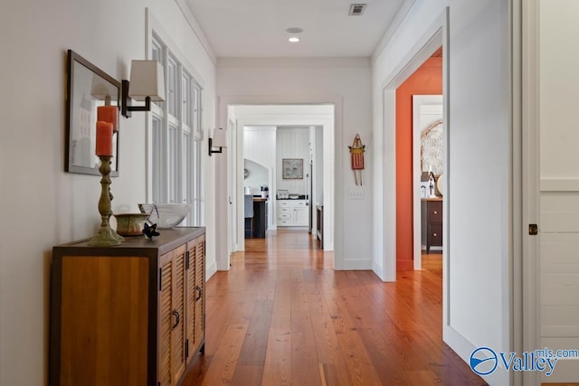 hallway featuring recessed lighting, baseboards, visible vents, wood finished floors, and arched walkways