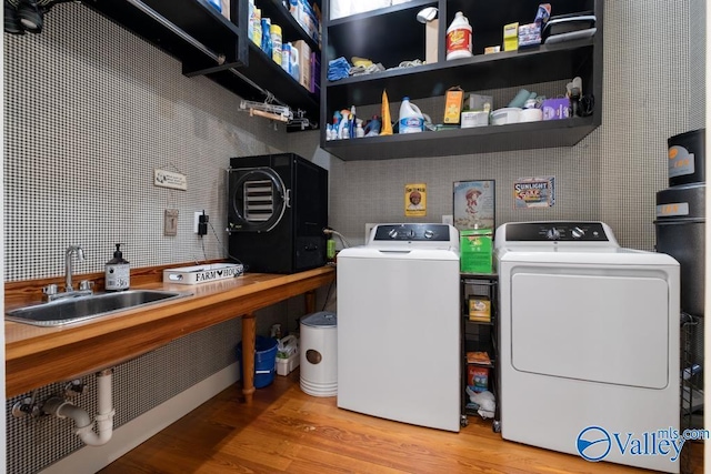 laundry room featuring light wood-type flooring, laundry area, independent washer and dryer, and a sink