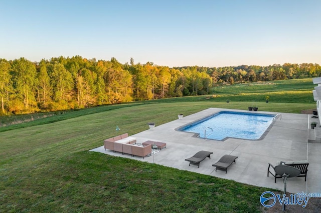 pool with a yard, a patio area, and a forest view