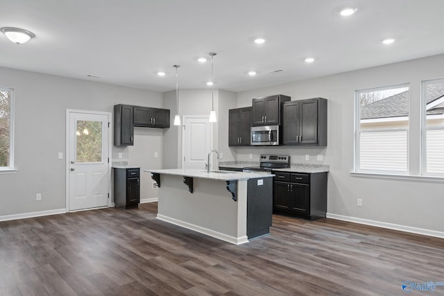 kitchen featuring stainless steel appliances, sink, pendant lighting, a kitchen island with sink, and dark wood-type flooring