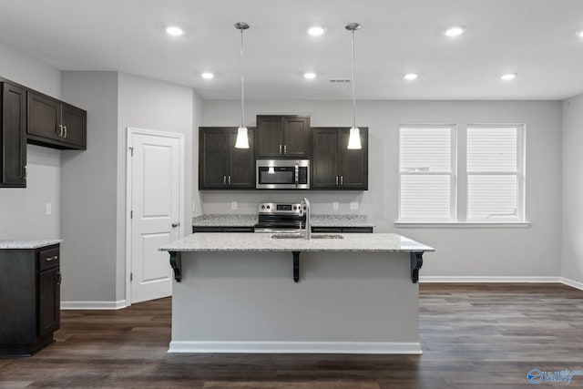 kitchen featuring hanging light fixtures, a kitchen island with sink, dark hardwood / wood-style floors, and stainless steel appliances