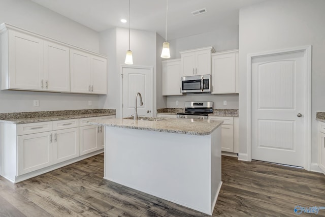 kitchen featuring a kitchen island with sink, stainless steel appliances, hanging light fixtures, sink, and white cabinets