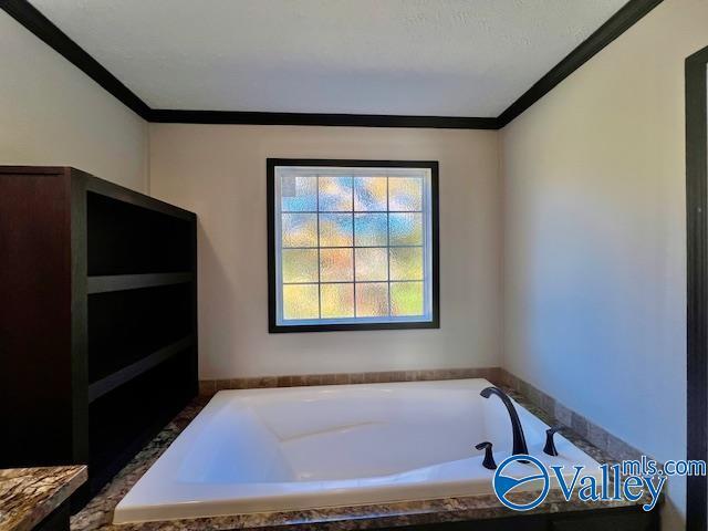 bathroom with crown molding and tiled tub