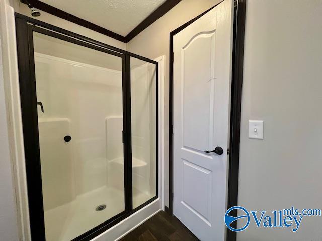 bathroom featuring wood-type flooring, ornamental molding, and a shower with shower door