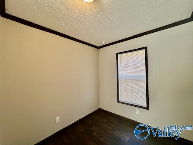 unfurnished room with dark hardwood / wood-style floors, crown molding, and a textured ceiling