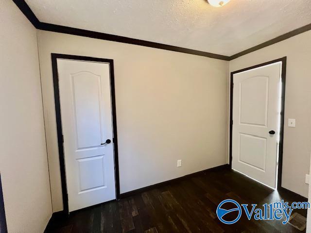 empty room featuring a textured ceiling, dark hardwood / wood-style flooring, and crown molding