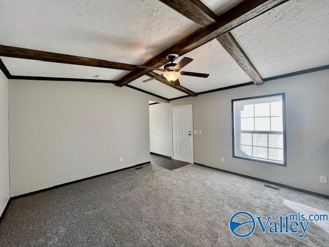 spare room with a textured ceiling, lofted ceiling with beams, ceiling fan, and carpet floors